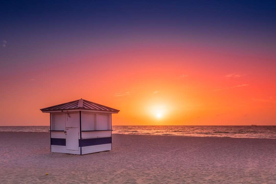 Bílý dřevěný dům na pláži při západu slunce online puzzle