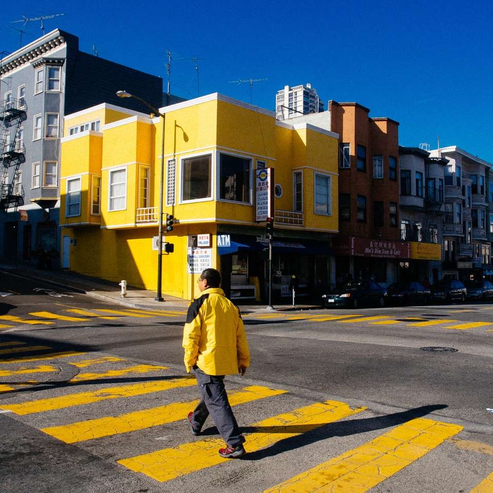 человек в желтой куртке идет по тротуару в дневное время пазл онлайн