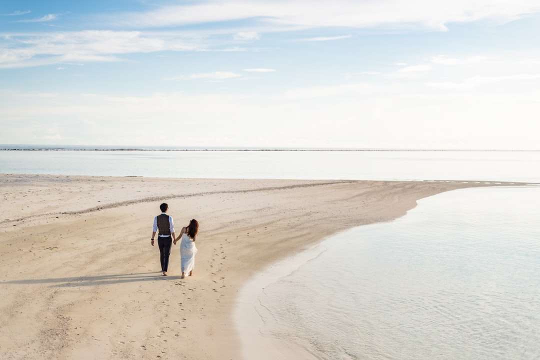 2 mujeres y hombre caminando en la playa durante el día rompecabezas en línea
