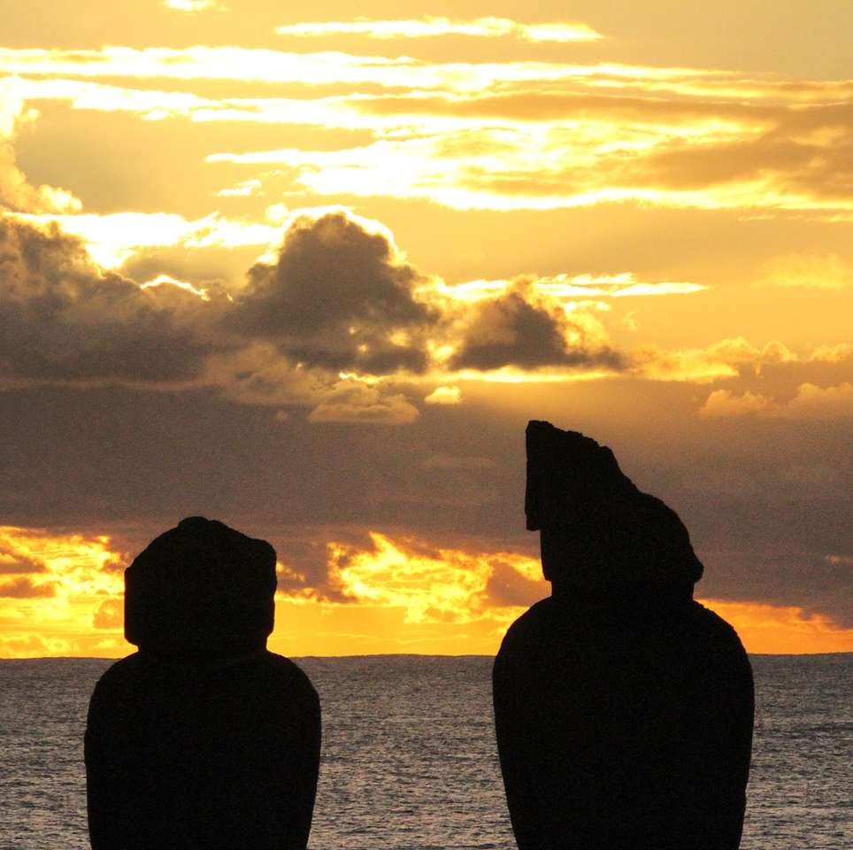 silhouette of two rock formation on body of water online puzzle