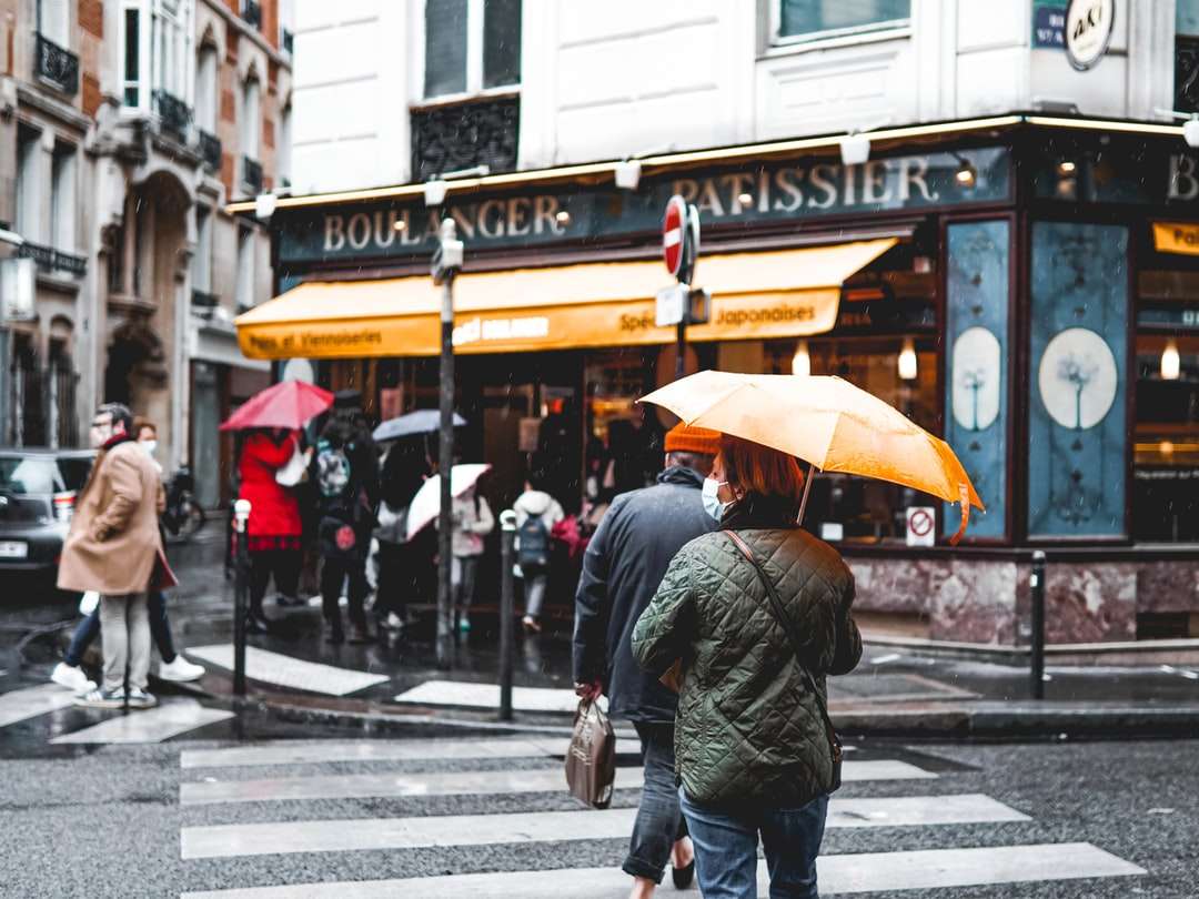 Mann in der schwarzen Jacke, die Regenschirm hält, der auf Bürgersteig geht Puzzlespiel online