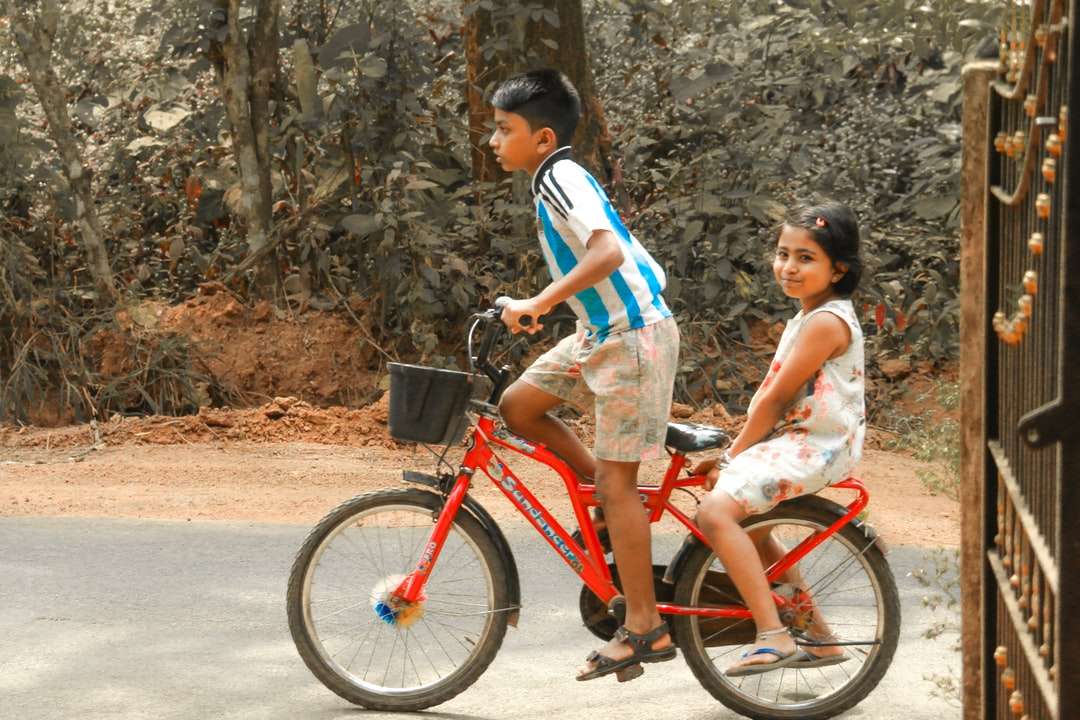 Chica en blanco y azul camiseta sin mangas montando en bicicleta roja rompecabezas en línea