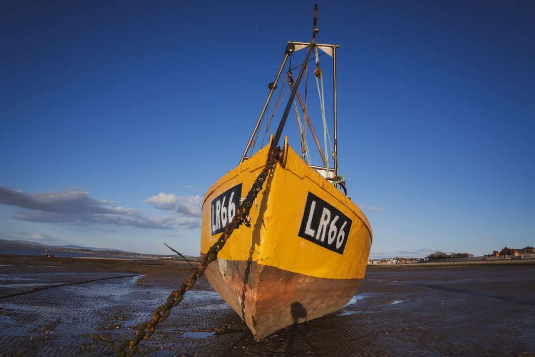 Barco amarelo e preto na areia marrom durante o dia puzzle online