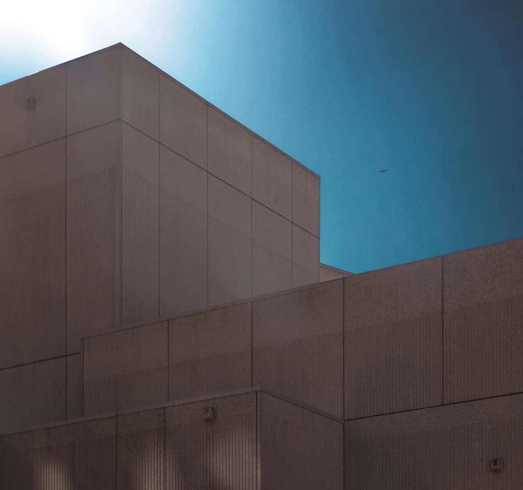 Šedá betonová budova pod modrou oblohou během dne skládačky online