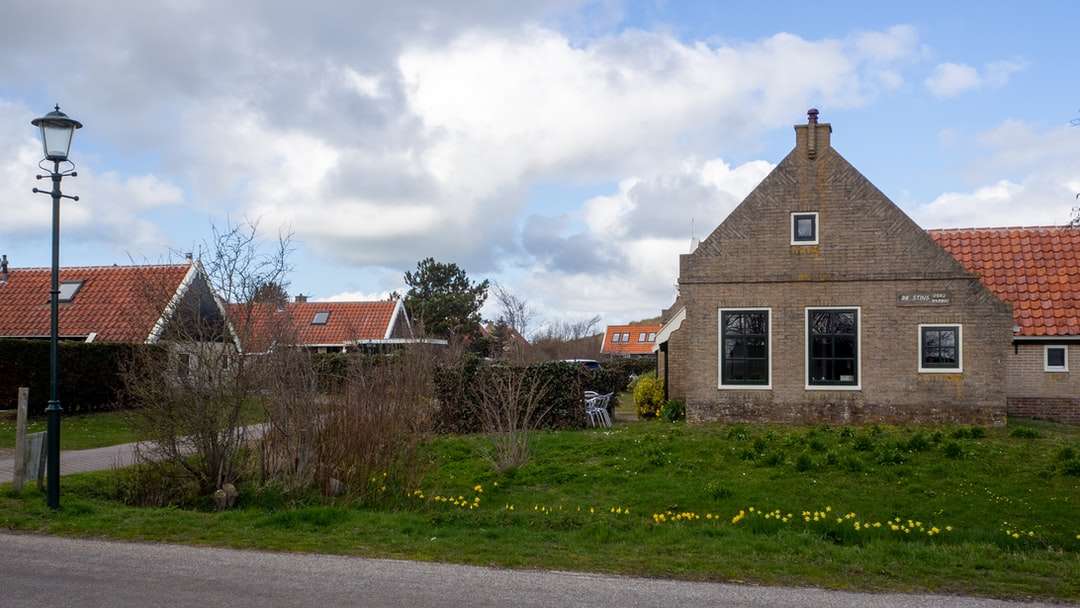 Maison de béton marron et blanc près du champ d'herbe verte puzzle en ligne