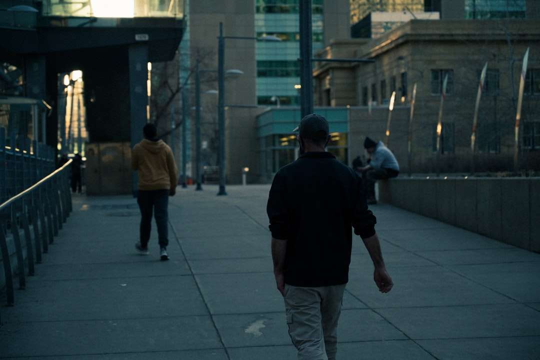Uomo in camicia nera e pantaloni grigi che camminano sul marciapiede puzzle online