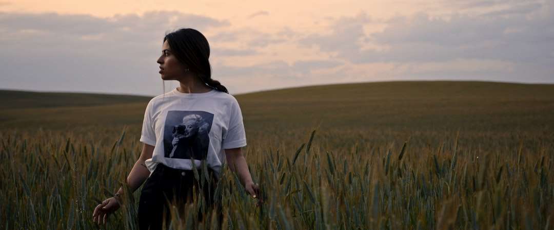 Kvinna i vit t-shirt som står på grönt gräsfält pussel på nätet