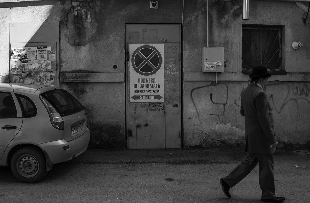 фото в оттенках серого человека, идущего по тротуару возле машины онлайн-пазл