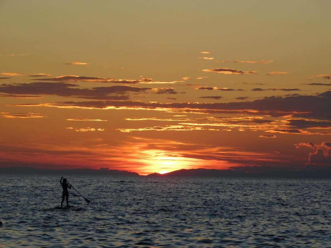 Σιλουέτα του ανθρώπου που στέκεται στην ακτή της θάλασσας κατά τη διάρκεια του ηλιοβασιλέματος παζλ online