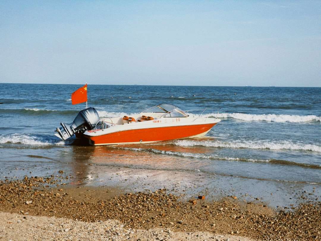 Weißes und rotes Boot am Strand tagsüber Puzzlespiel online