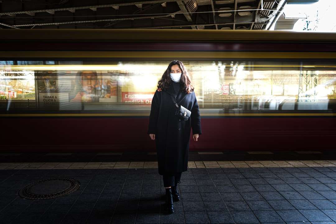 жінка в чорній сукні з довгим рукавом стоїть на вокзалі онлайн пазл