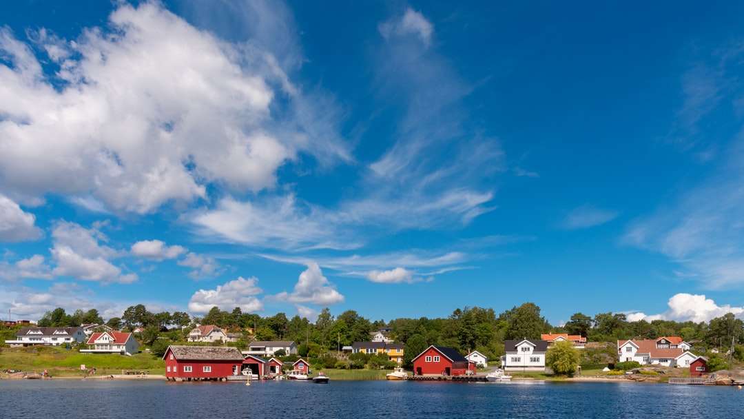 Rött och vitt hus nära vattenkropp under blå himmel Pussel online