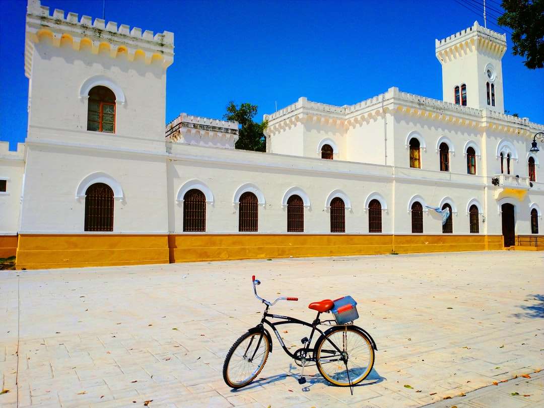 Bicicletta nera parcheggiata accanto all'edificio in cemento beige puzzle online