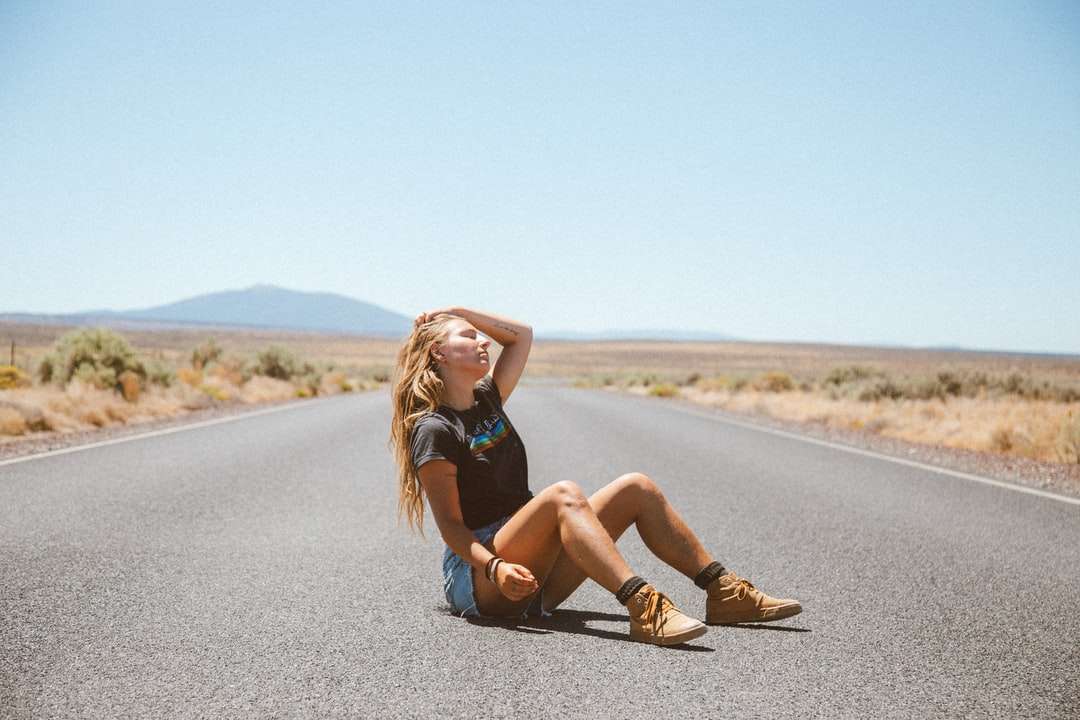 Mujer en top sin mangas negro y pantalones marrones sentados en la carretera rompecabezas en línea