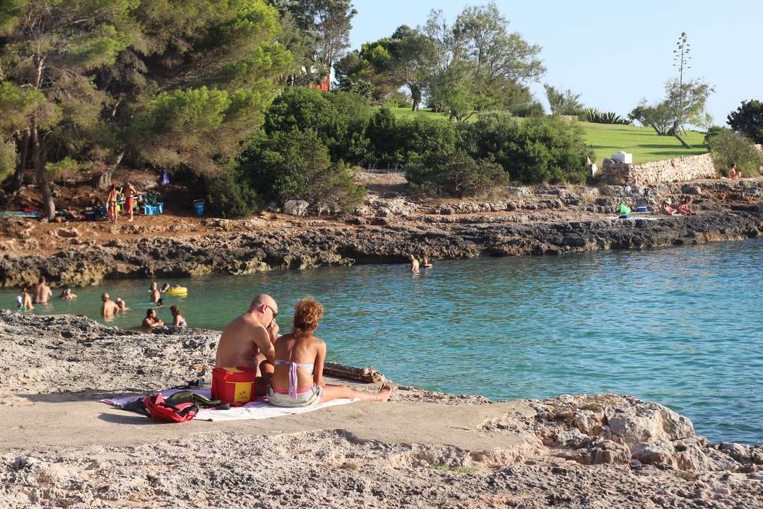 Frau im rosa Bikini, der auf Strandsand nahe Körper des Wassers liegt Online-Puzzle