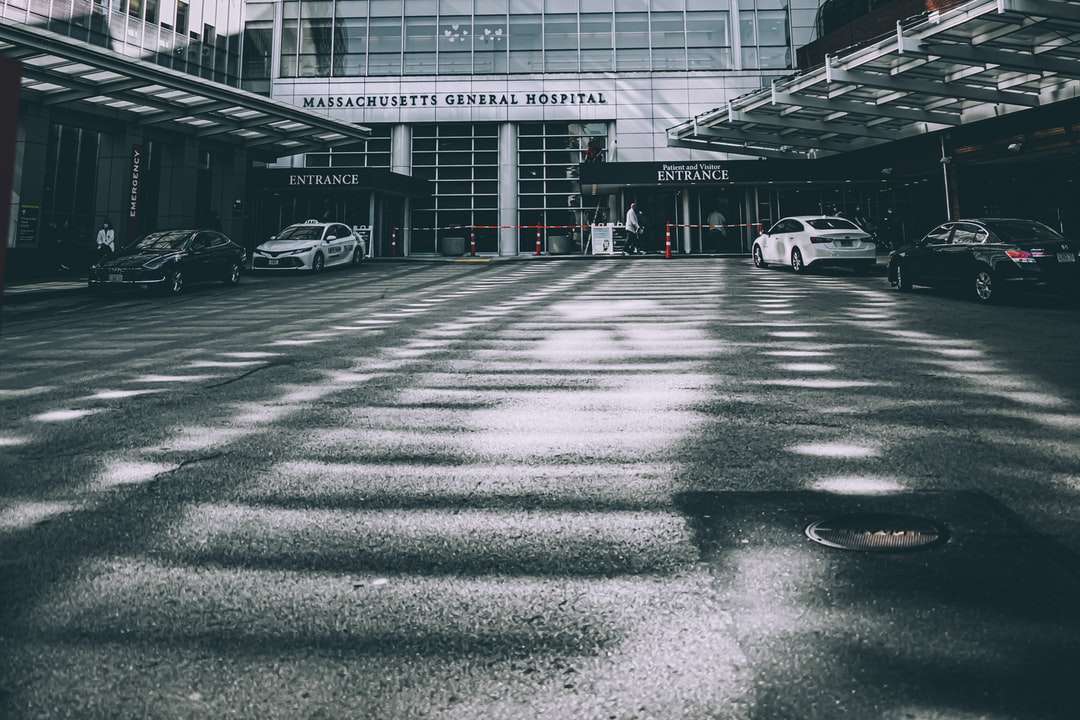 Foto en escala de grises de los coches estacionados frente al edificio. rompecabezas en línea