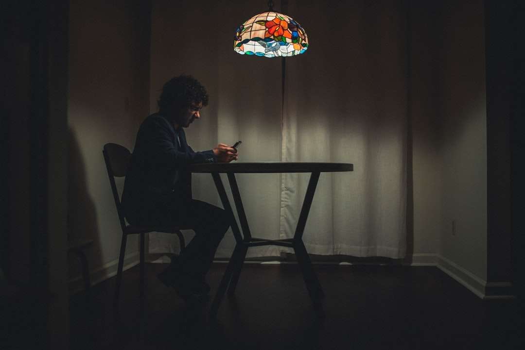 Mann im schwarzen Hemd, das auf Stuhl sitzt Online-Puzzle