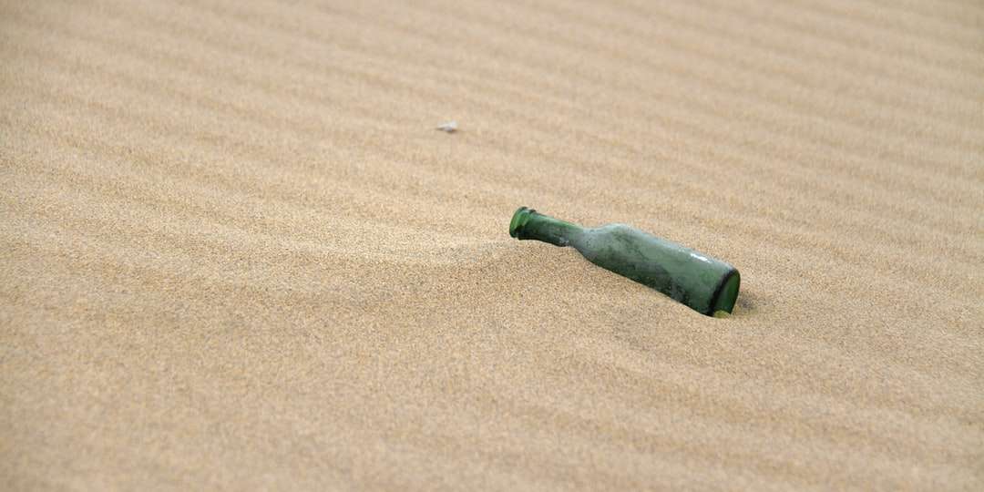Groene en zwarte glazen fles op bruin zand online puzzel