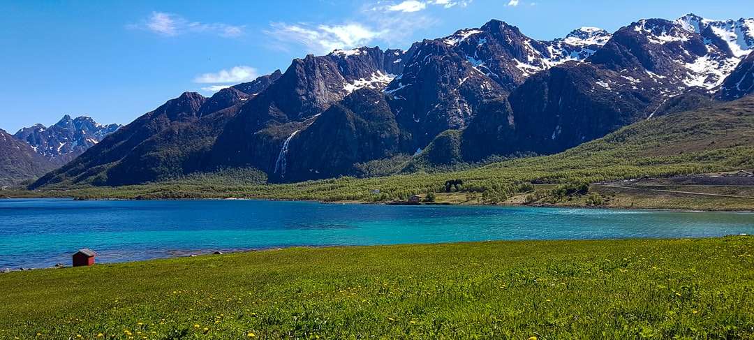 Zöld fűmező a tó és a hófödte hegy közelében kirakós online