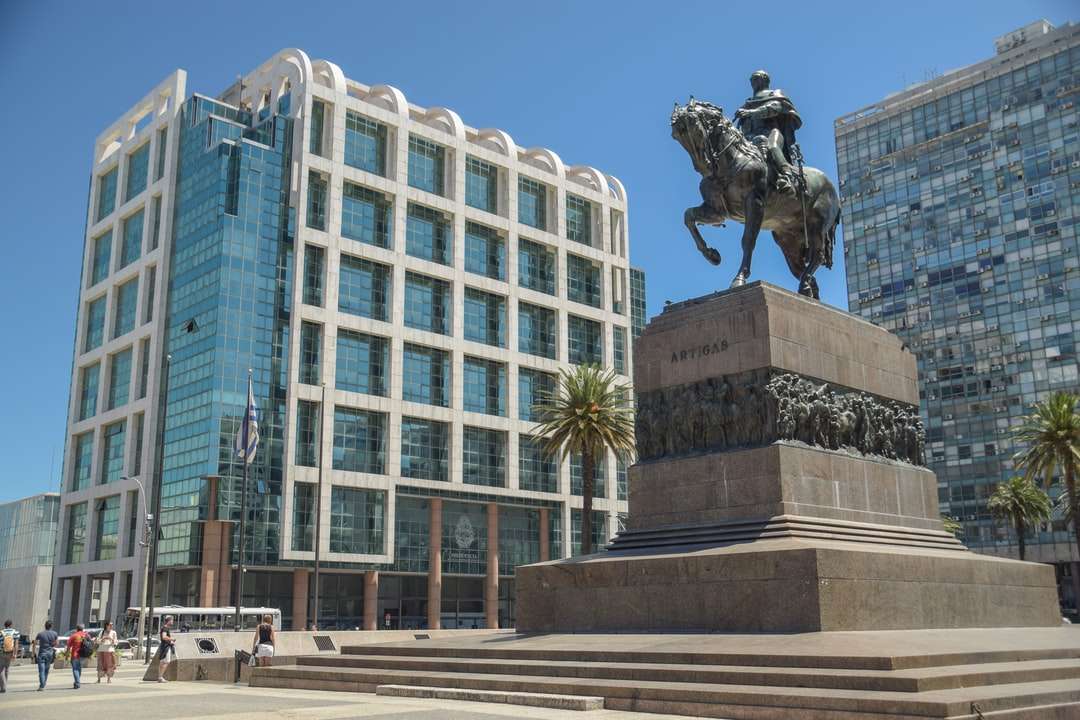 статуя человека верхом на лошади возле белого бетонного здания онлайн-пазл