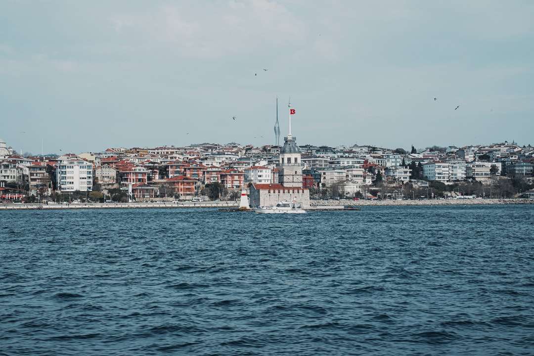 Bateau blanc sur mer près des bâtiments de la ville pendant la journée puzzle en ligne