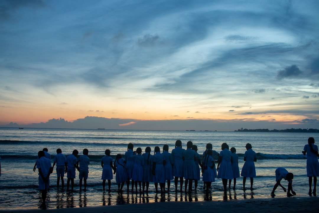 Människor som står på stranden under solnedgången Pussel online