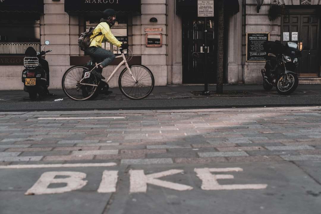 bărbat în cămașă galbenă mergând cu bicicleta pe trotuar puzzle online