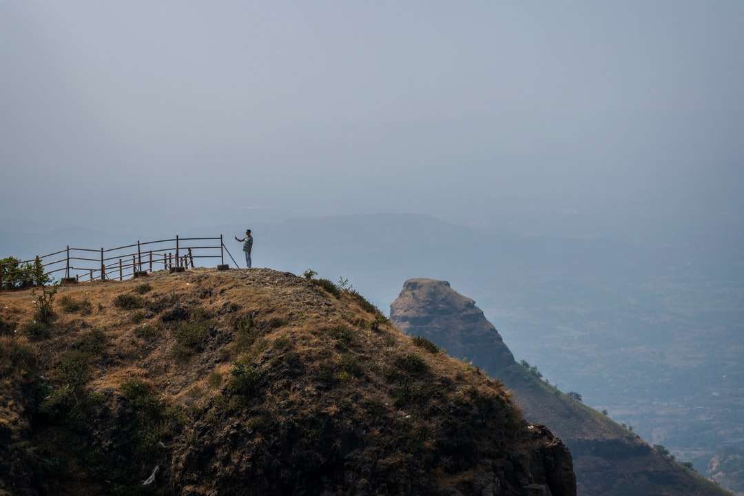 Persona in piedi in cima alla montagna durante il giorno puzzle online
