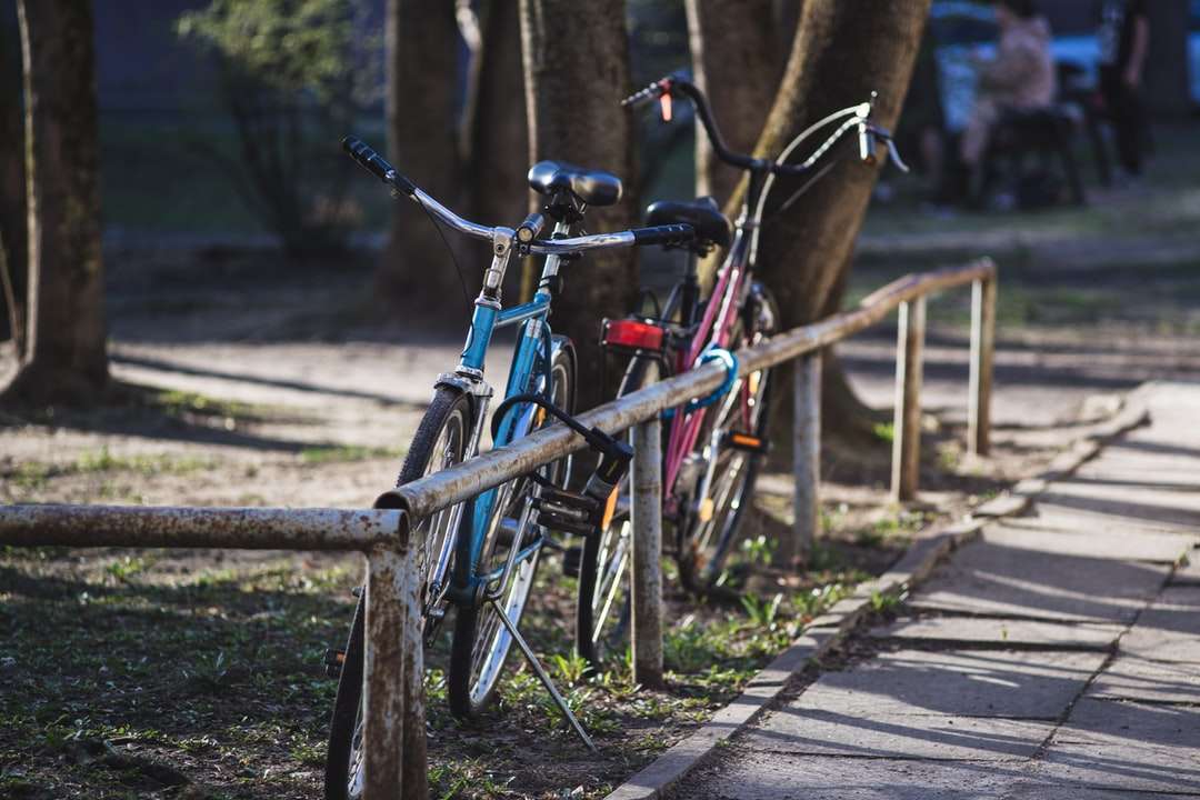 сини и черни градски велосипеди, паркирани върху кафява дървена ограда онлайн пъзел