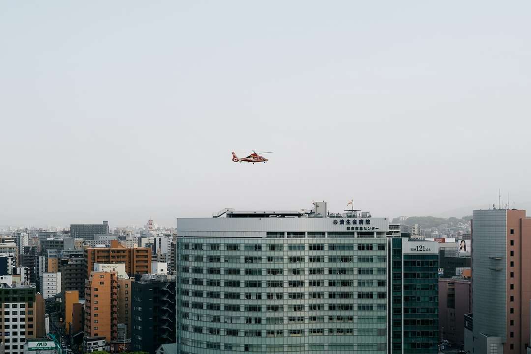 бял самолет, летящ над градските сгради през деня онлайн пъзел