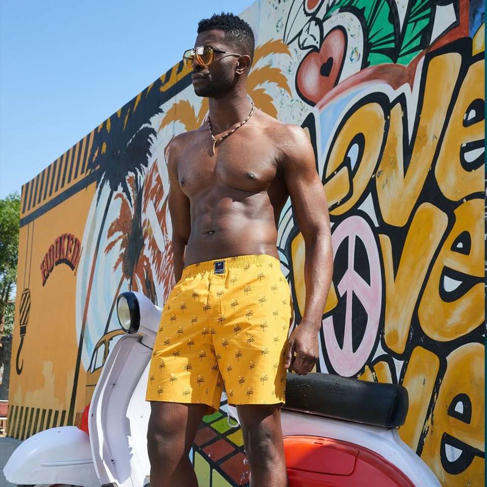 Hombre en pantalones cortos amarillos y rojos de pie junto a la pared de graffiti. rompecabezas en línea