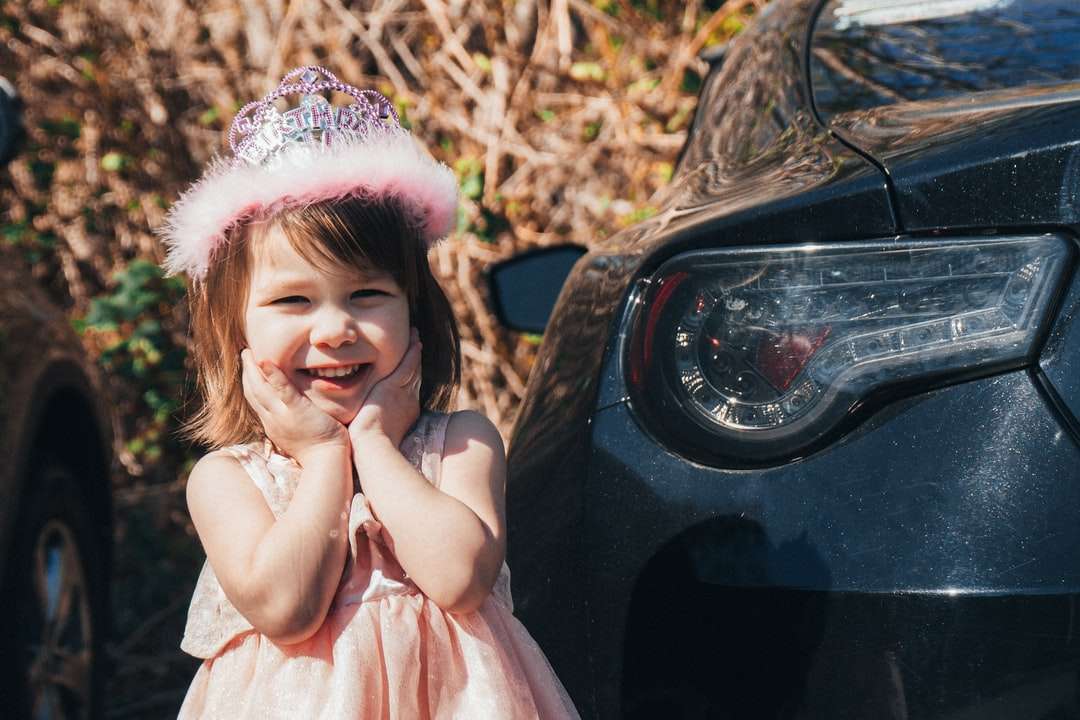 rózsaszín ruhás lány fekete autón ül kirakós online