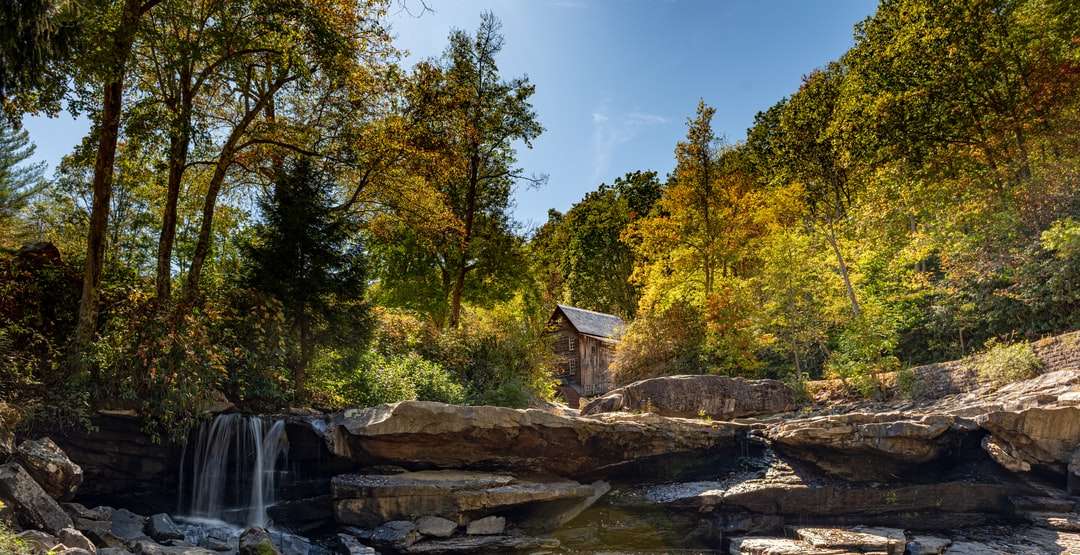 Casa de lemn maro pe rock gri lângă copaci verzi puzzle online
