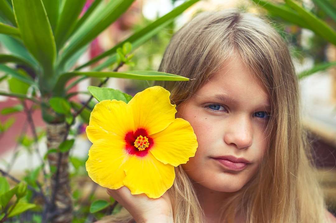 Dívka drží žlutý květ během dne online puzzle
