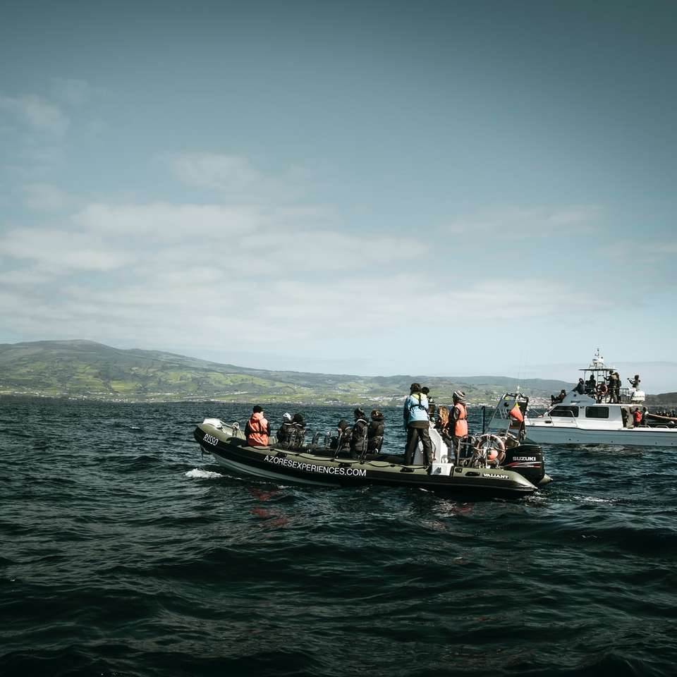 Personas que montan en barco negro y rojo en el mar durante el día rompecabezas en línea