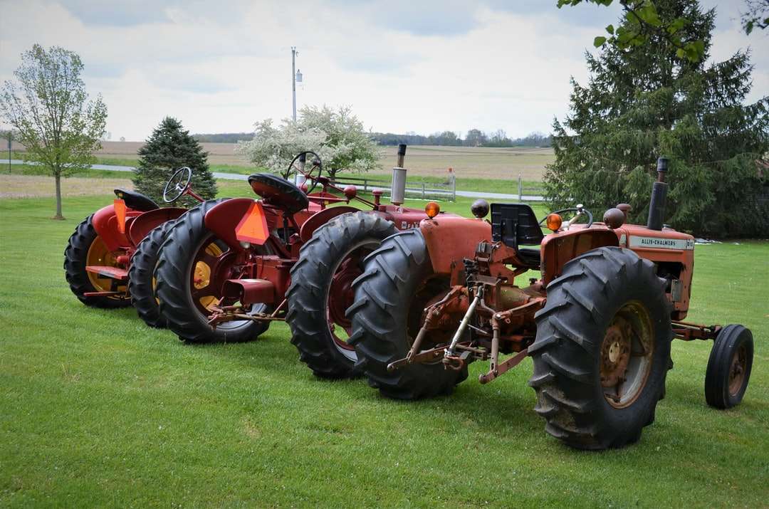 röd traktor på grönt gräsfält under dagtid Pussel online