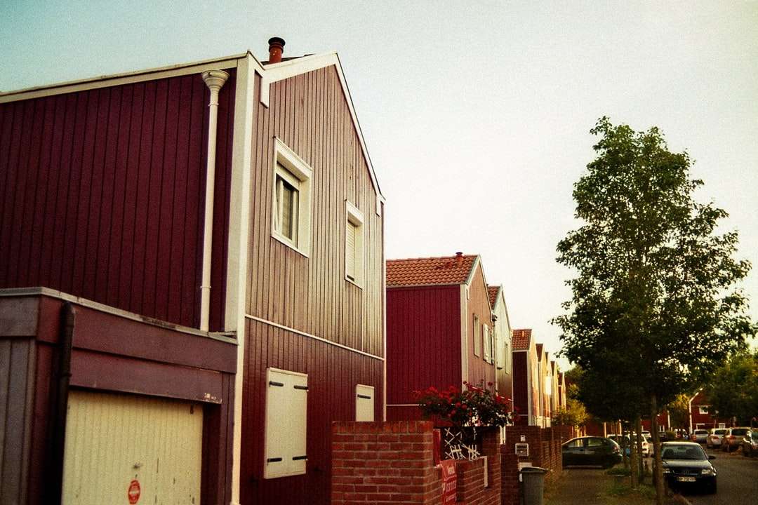 Casa in legno rossa e bianca vicino agli alberi verdi durante il giorno puzzle online