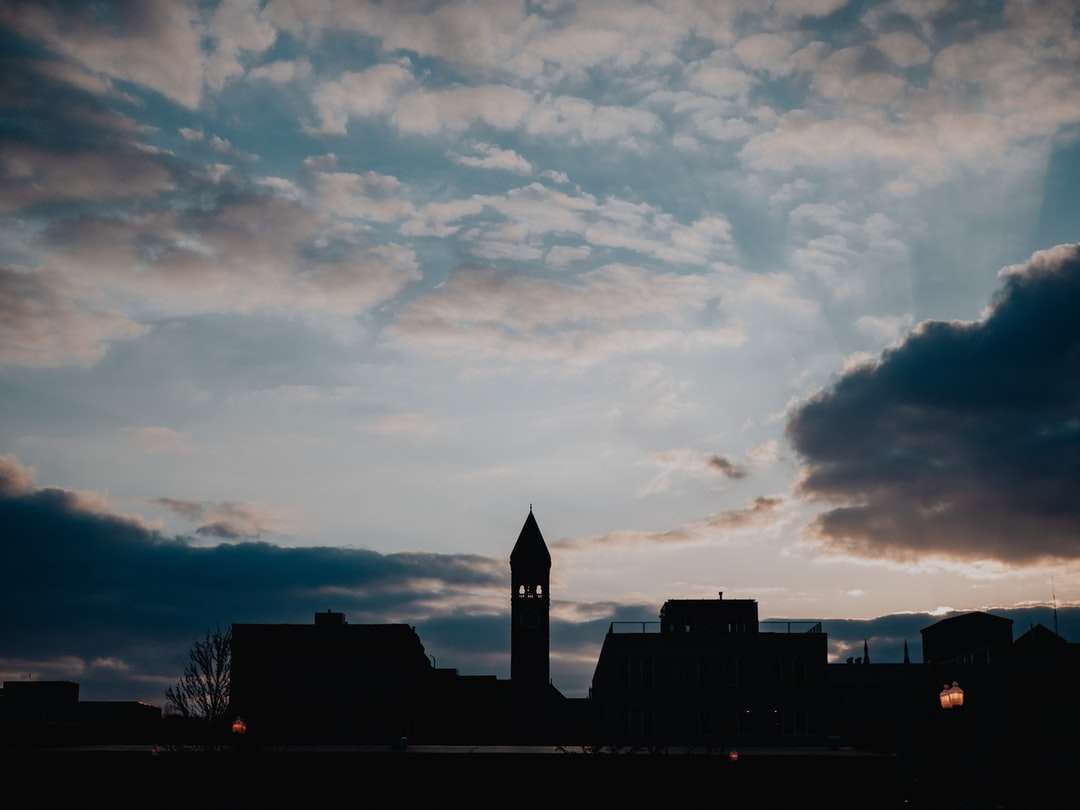 silhouet van gebouw onder bewolkte hemel tijdens zonsondergang online puzzel