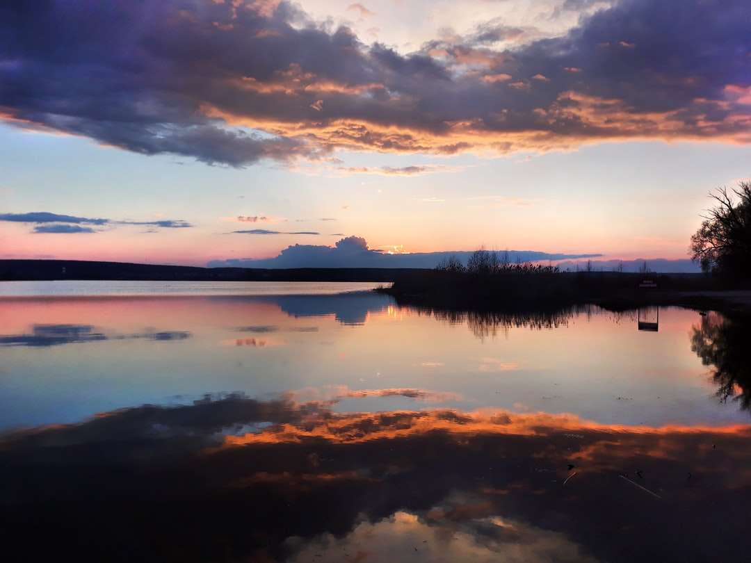 Lichaam van water onder bewolkte hemel tijdens zonsondergang online puzzel