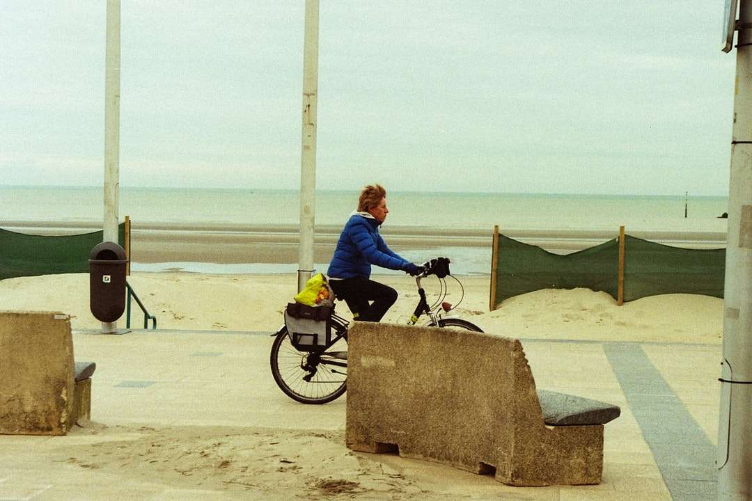 Muž v modré bundě na černém motocyklu na pláži online puzzle