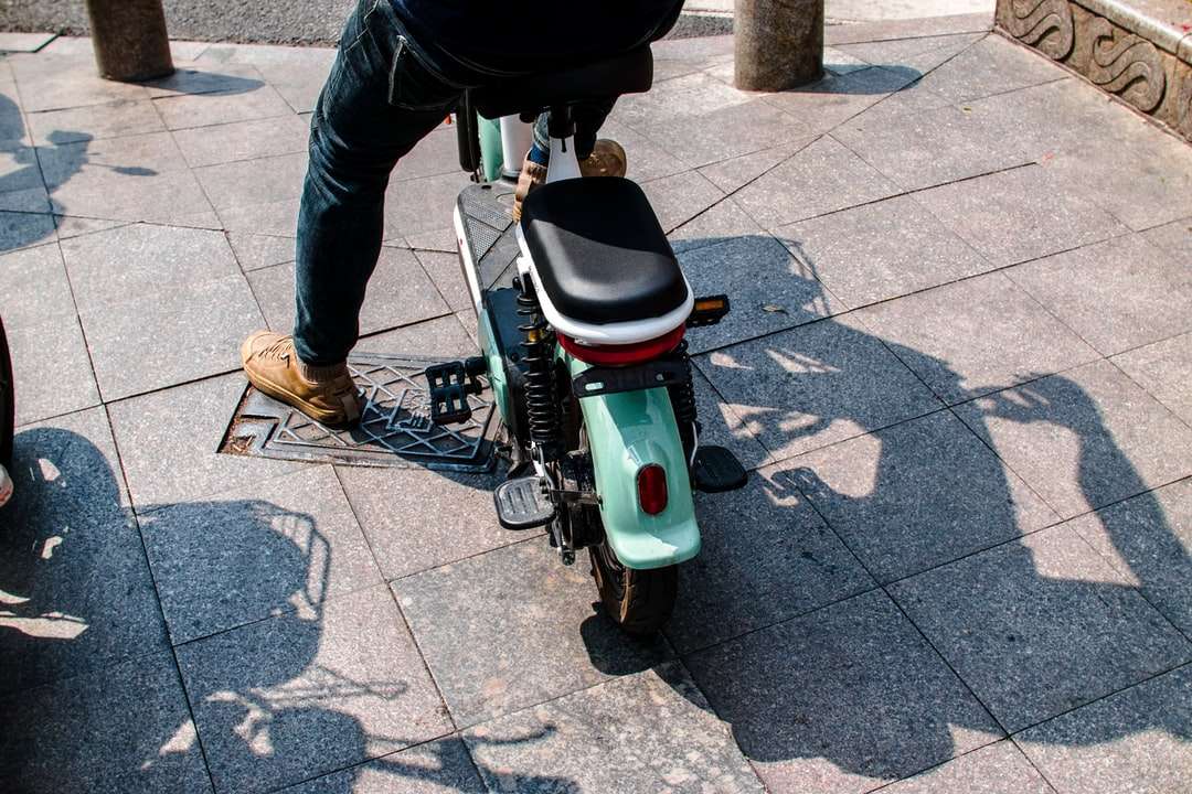 Persona en chaqueta negra montando scooter de motor blanco y verde rompecabezas en línea