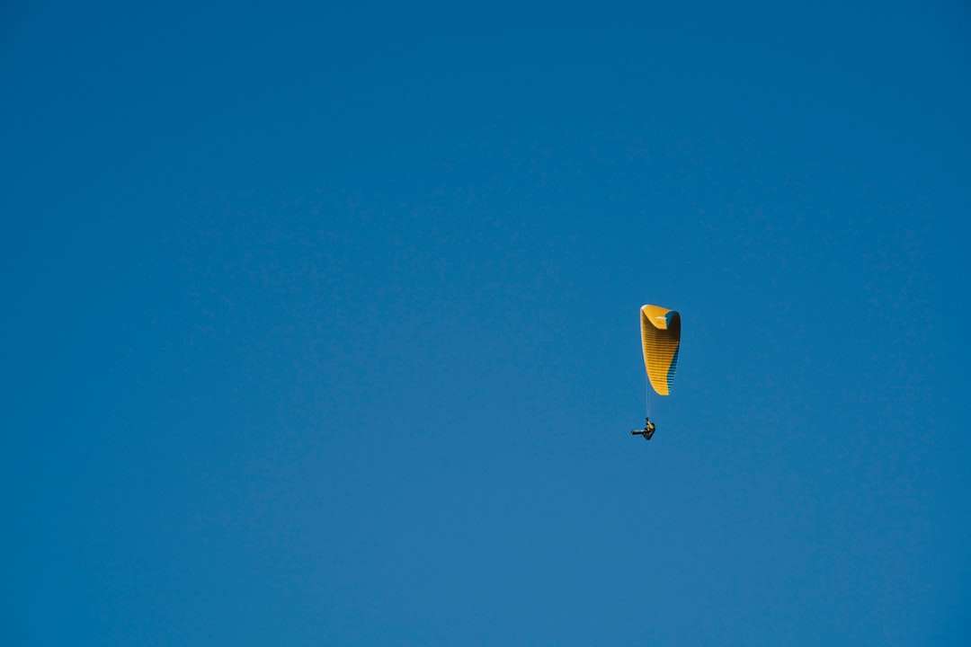 Gul och grön varmluftsballong i mitten av luften under blå himmel pussel på nätet