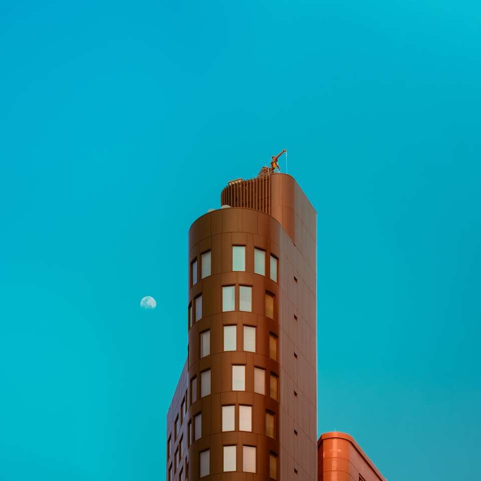 Edifício de concreto marrom sob o céu azul durante o dia quebra-cabeças online
