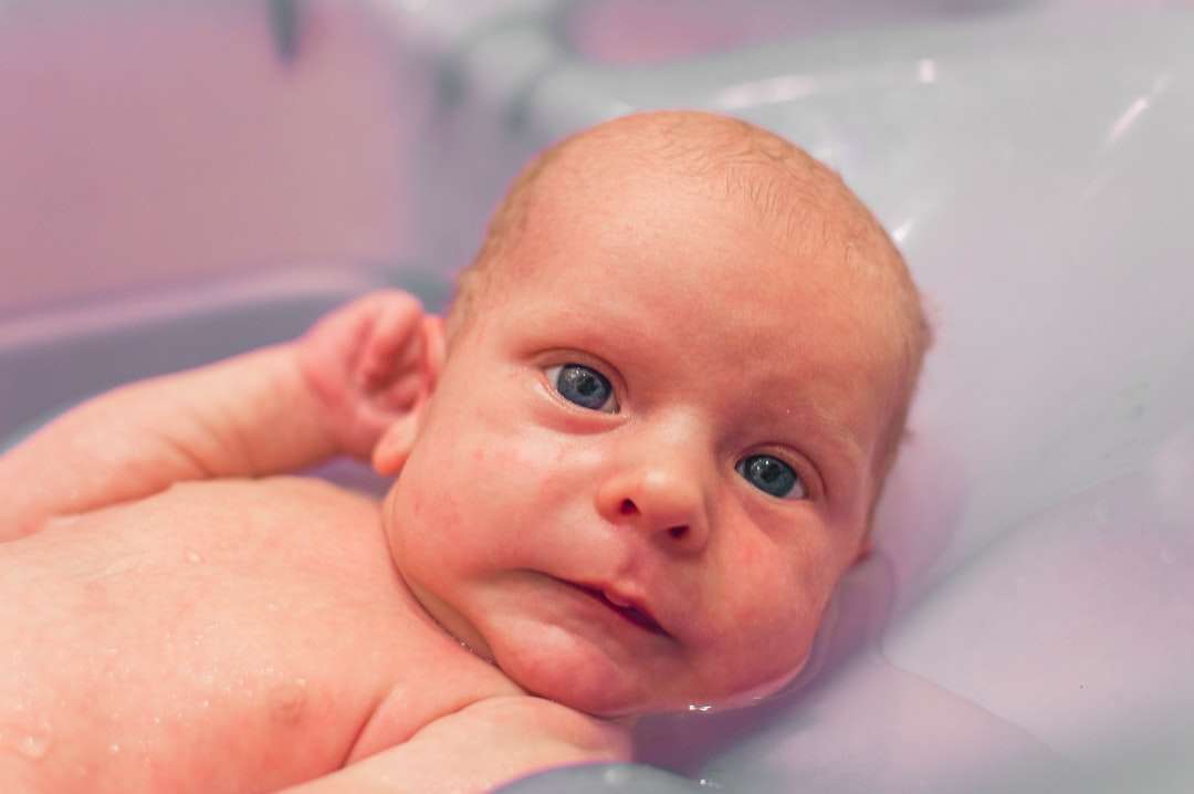 Baby ligger på vitt badkar Pussel online