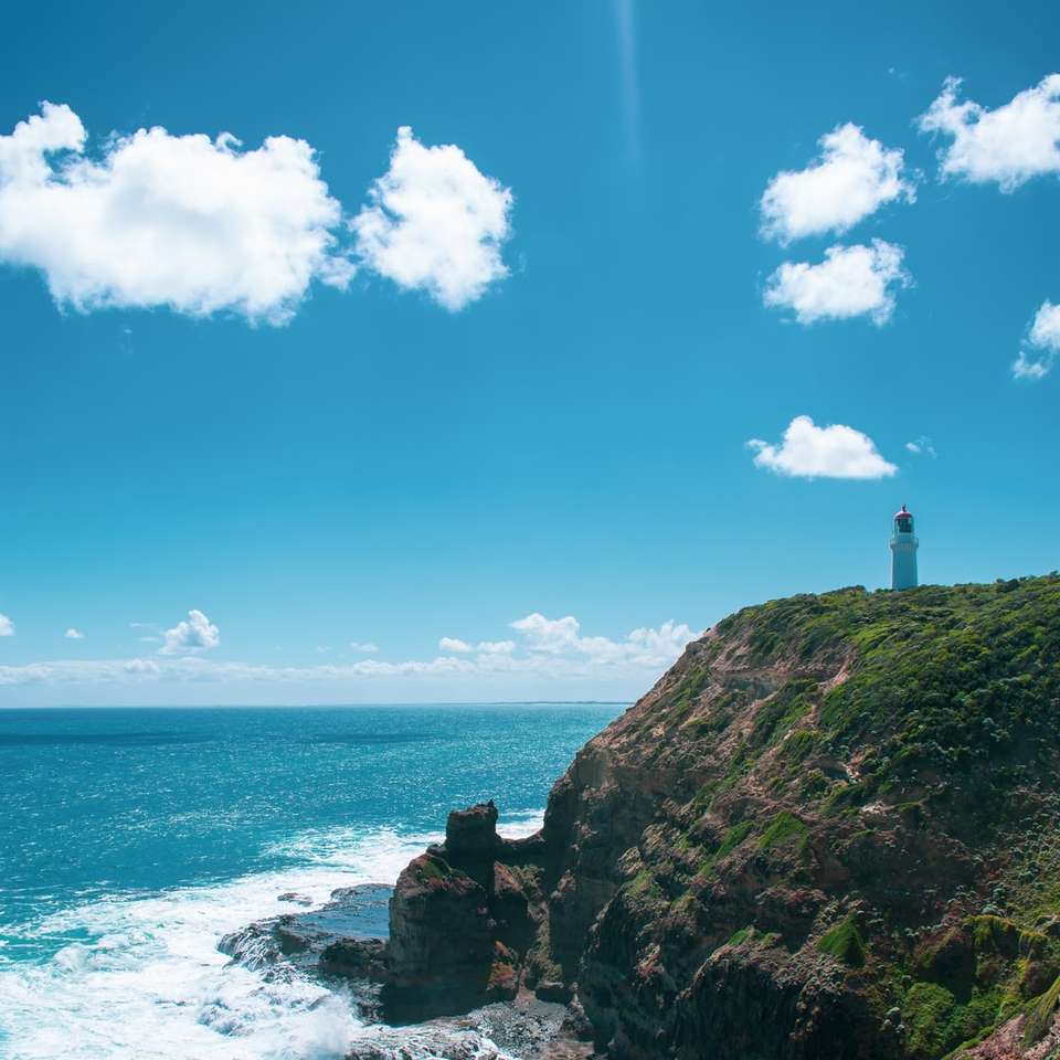 Sziluettje a világítótorony sziklán a tengeren online puzzle