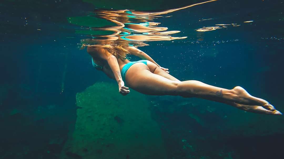 Vrouw in blauwe bikini die in water zwemmen online puzzel