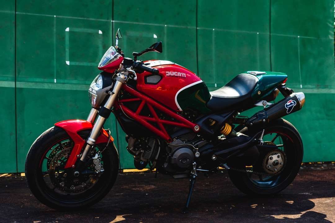 Röd och svart sportcykel parkerad bredvid grön vägg pussel på nätet