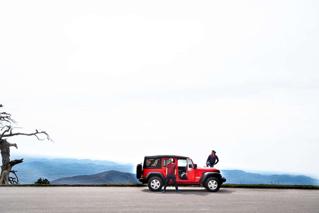 2 bărbați care stau pe Red Jeep Wrangler pe plajă jigsaw puzzle online