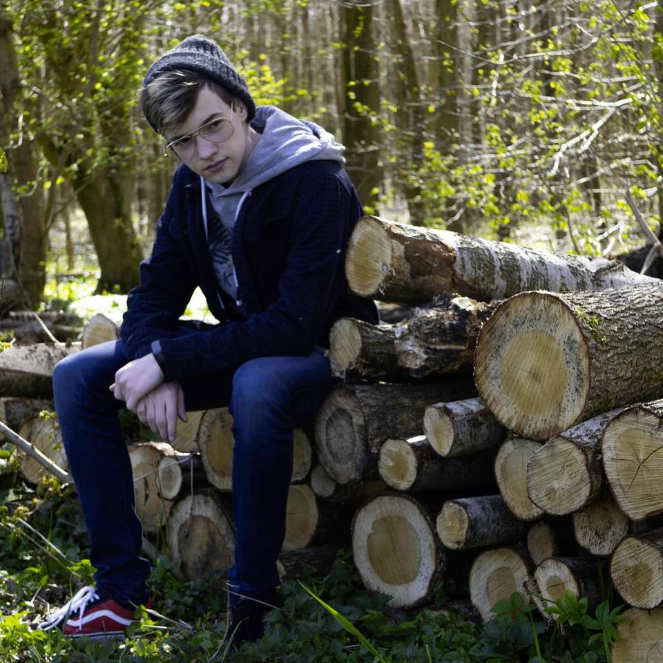 Man in zwarte jas zittend op bruin hout logboek online puzzel