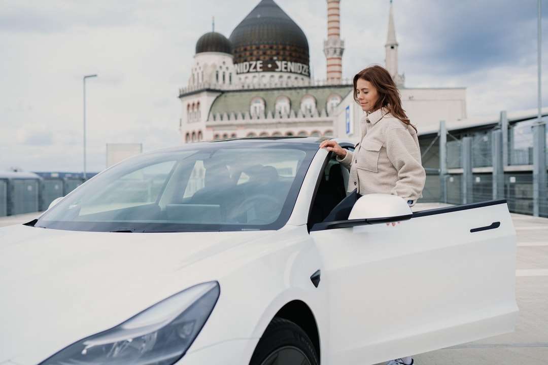 Vrouw in grijze blazer die zich naast witte auto bevindt legpuzzel online